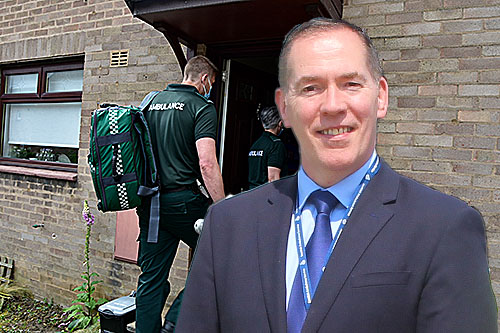 Michael Dickson in front of two Paramedics entering a house