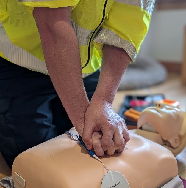 Two arms performing CPR on a CPR dummy.