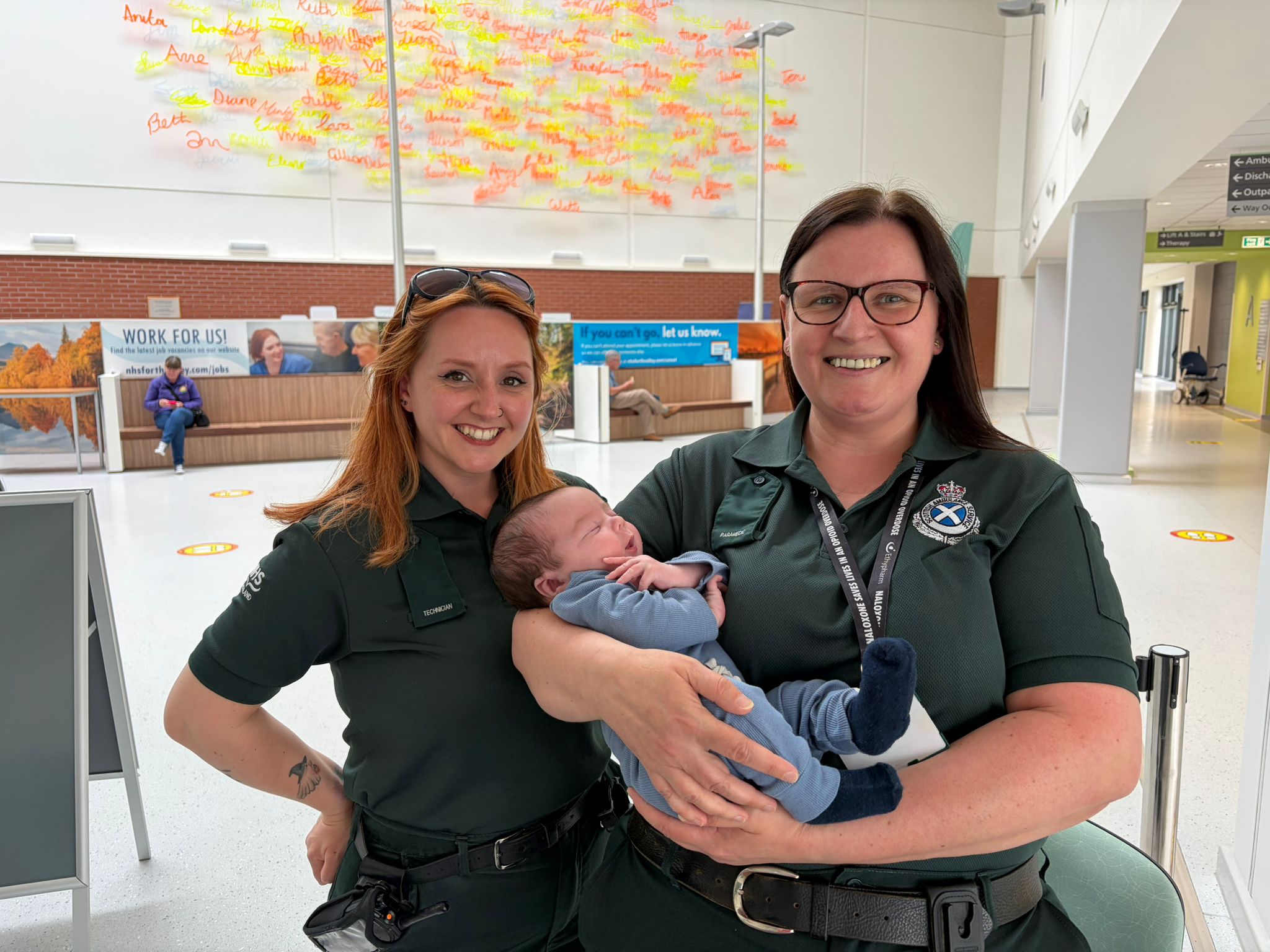 SAS staff members Samantha and Tracy hold baby Ally after helping deliver, and are smiling