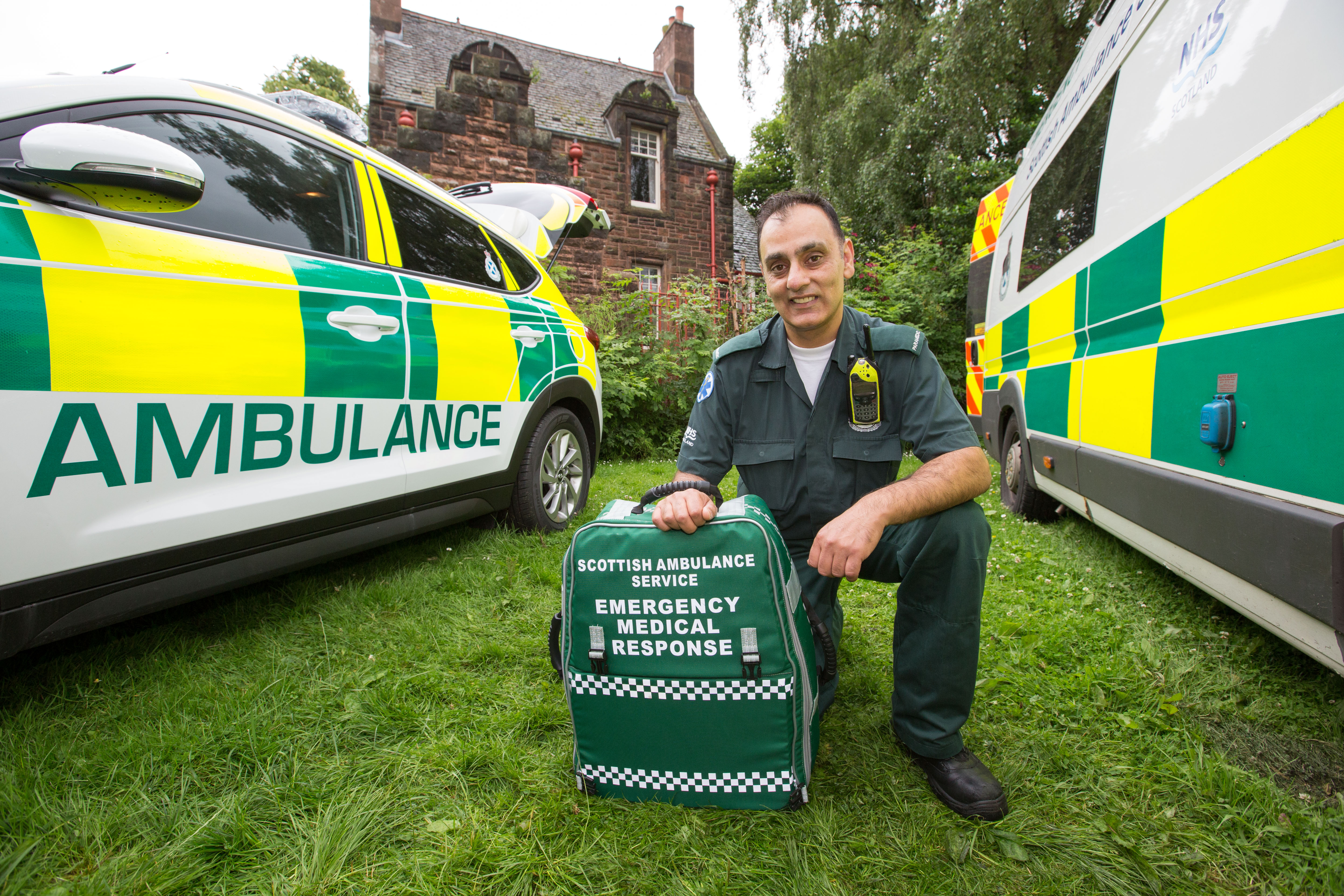 A Paramedic kneels between two ambulance vehicles