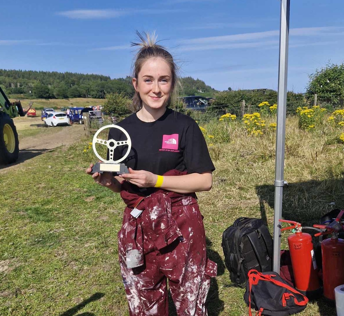 Nicole holding her trophy with cars in the background