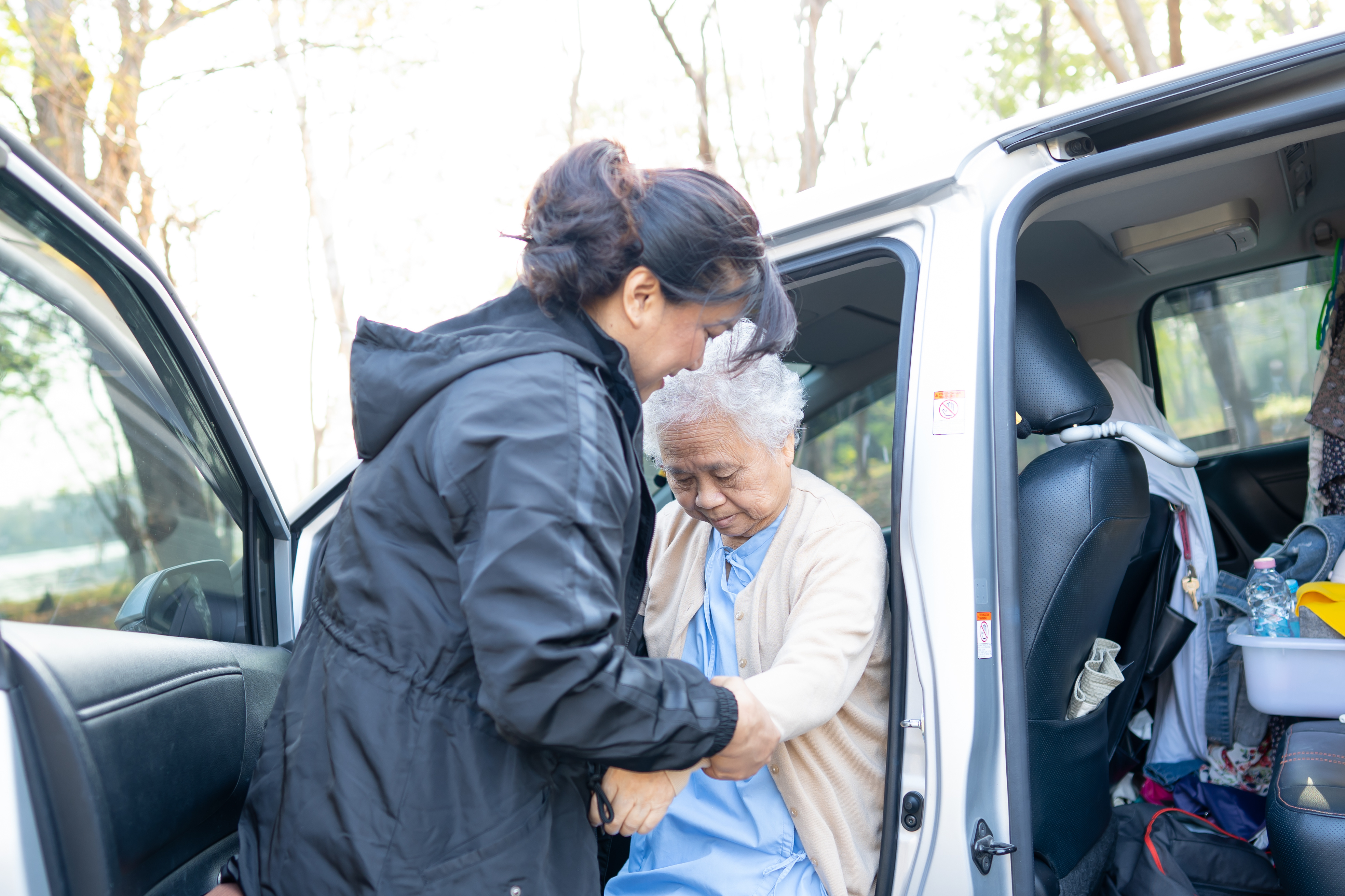 A lady helps her mum into a car