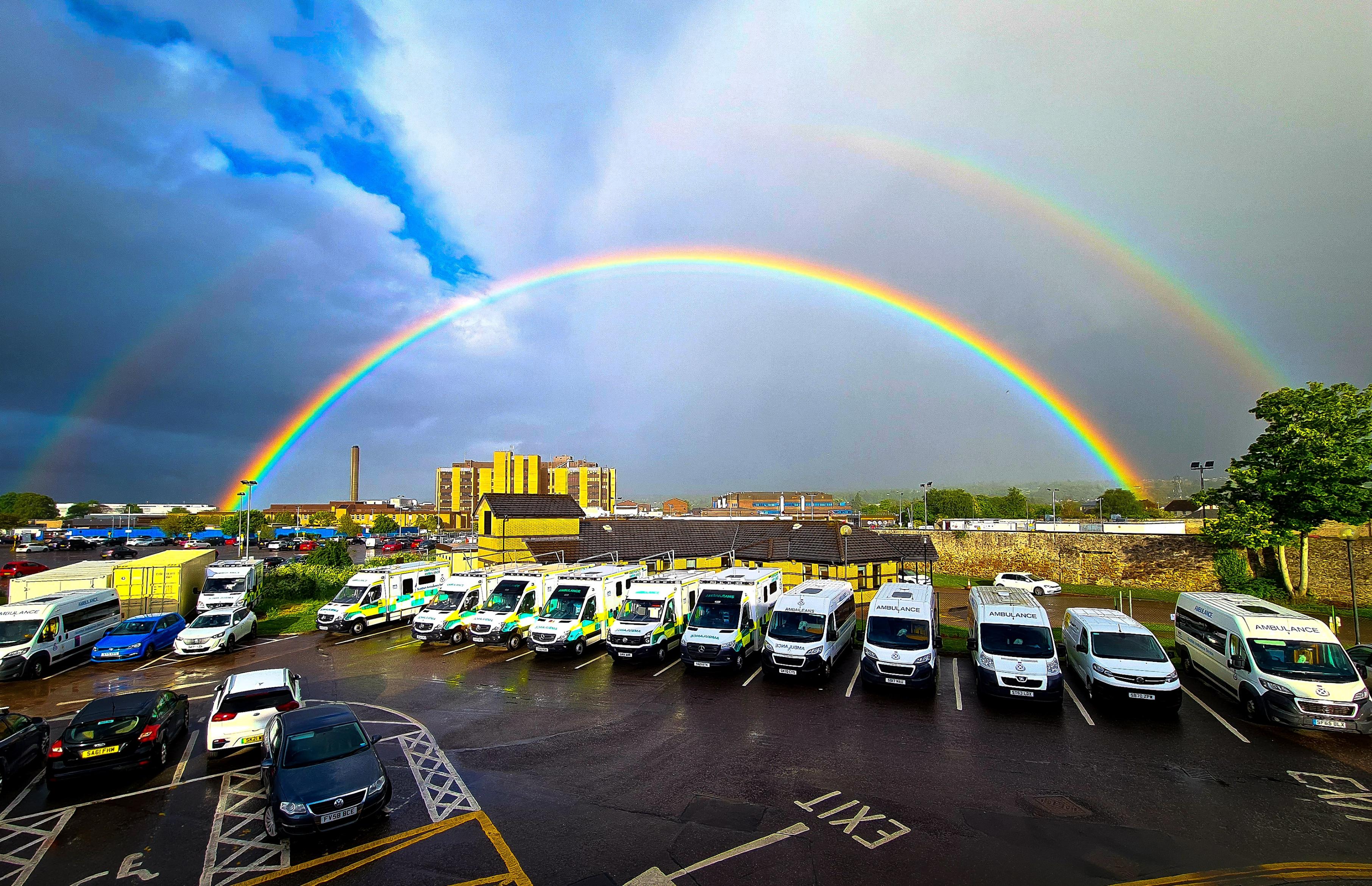 A car park full of ambulances with a rainbow above