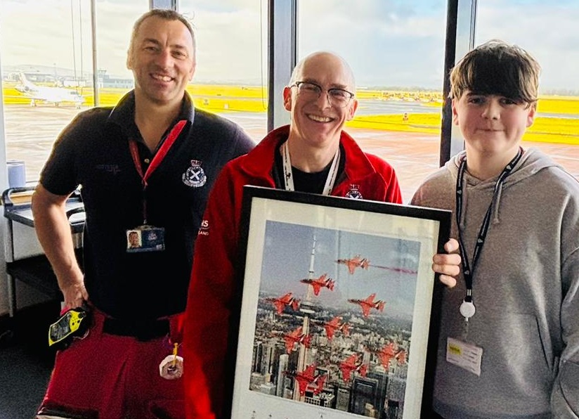Thomas Bell stands next to ScotSTAR staff who are holding up a picture of the red arrows