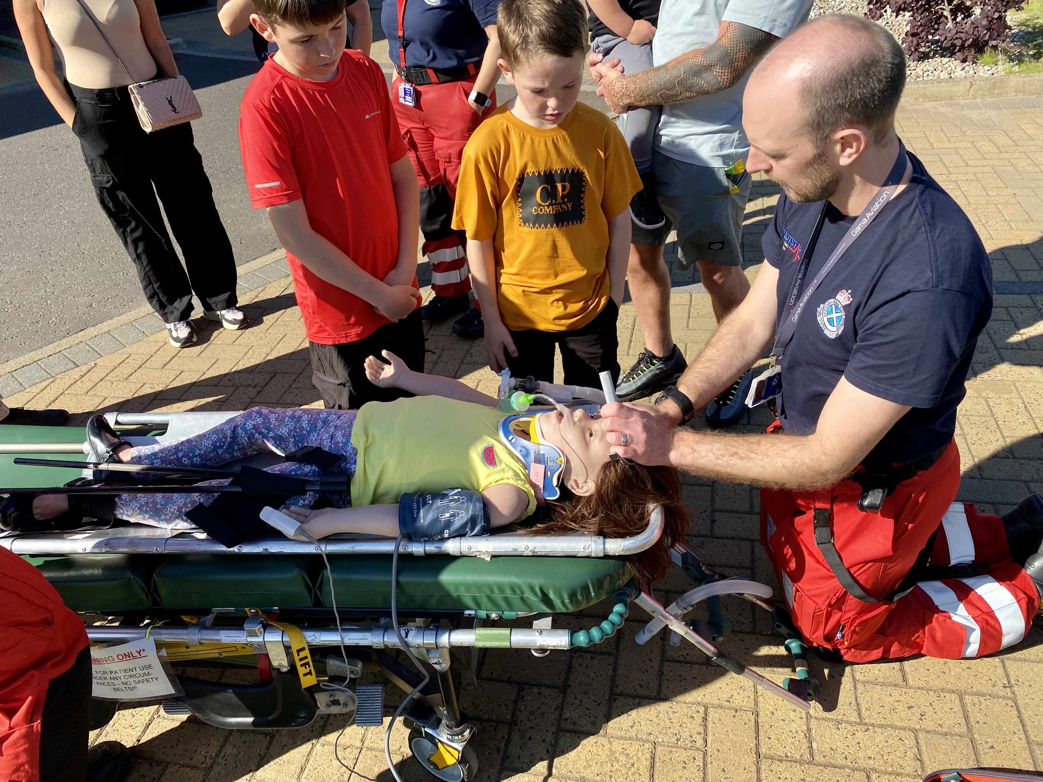 Scotstar paramedic demonstrates medical procedure on female dummy for two young boys.