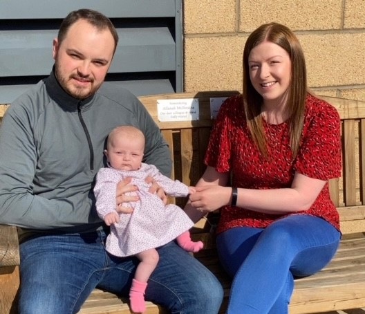 John and Laura, along with their daughter Lana sitting on the bench