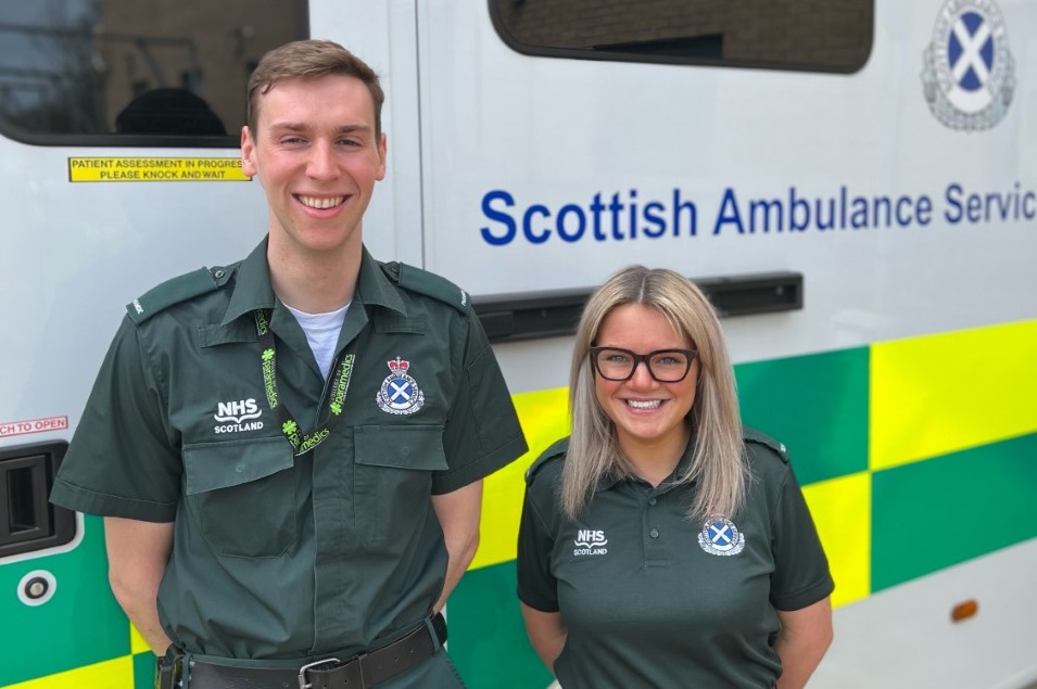 Two members of staff in front of an ambulance