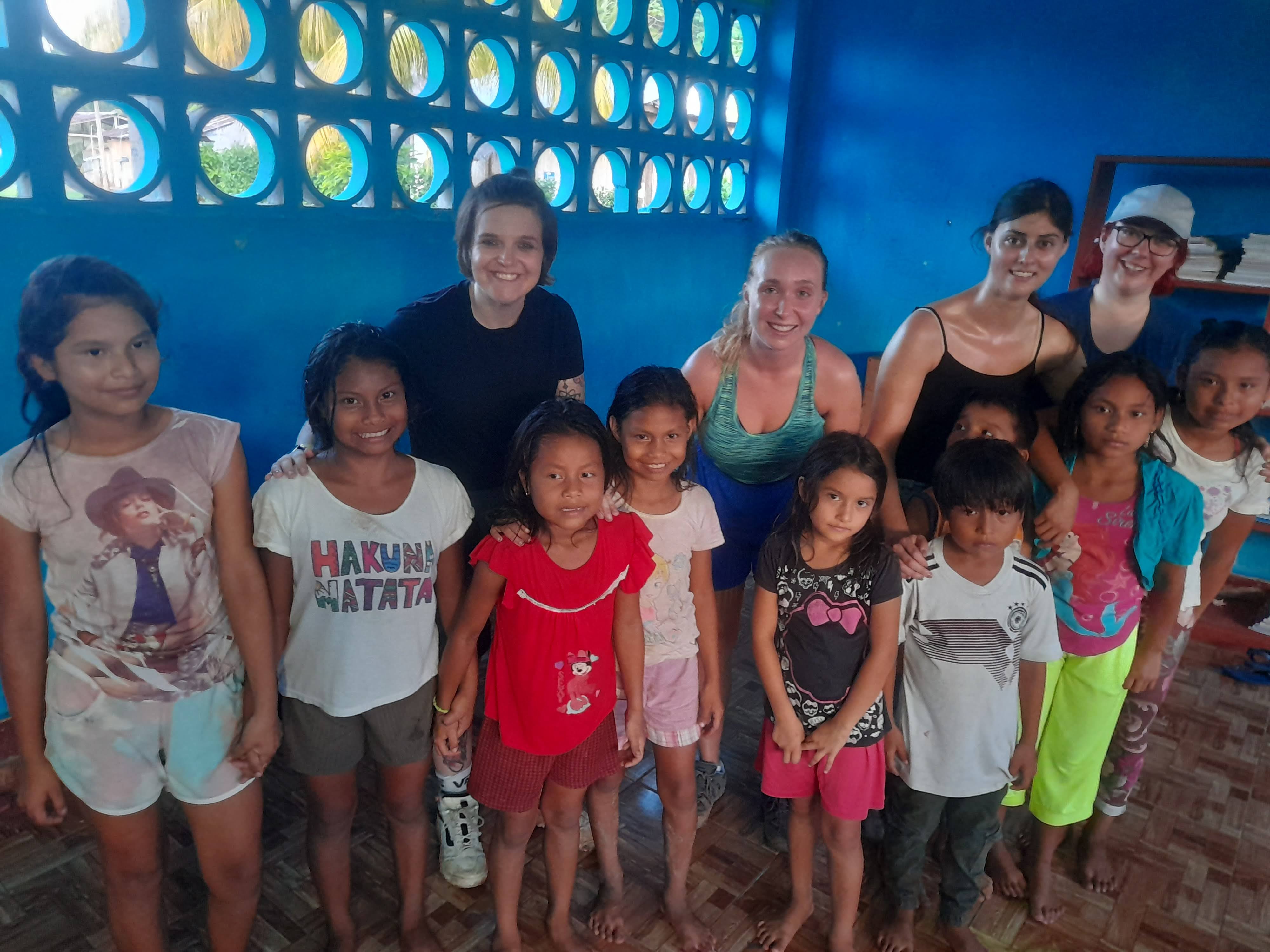 Kelly Irvine along 3 other female adult volunteers standing with group of children.