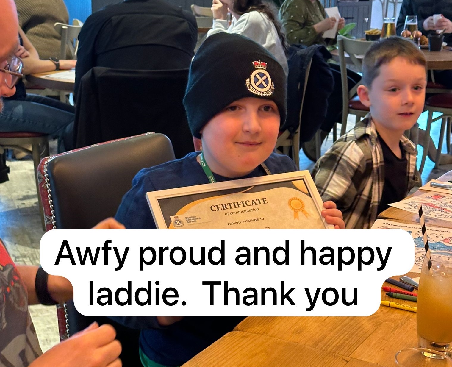 Murray showing his certificate with a sign saying Awfy proud and happy laddie. Thank you