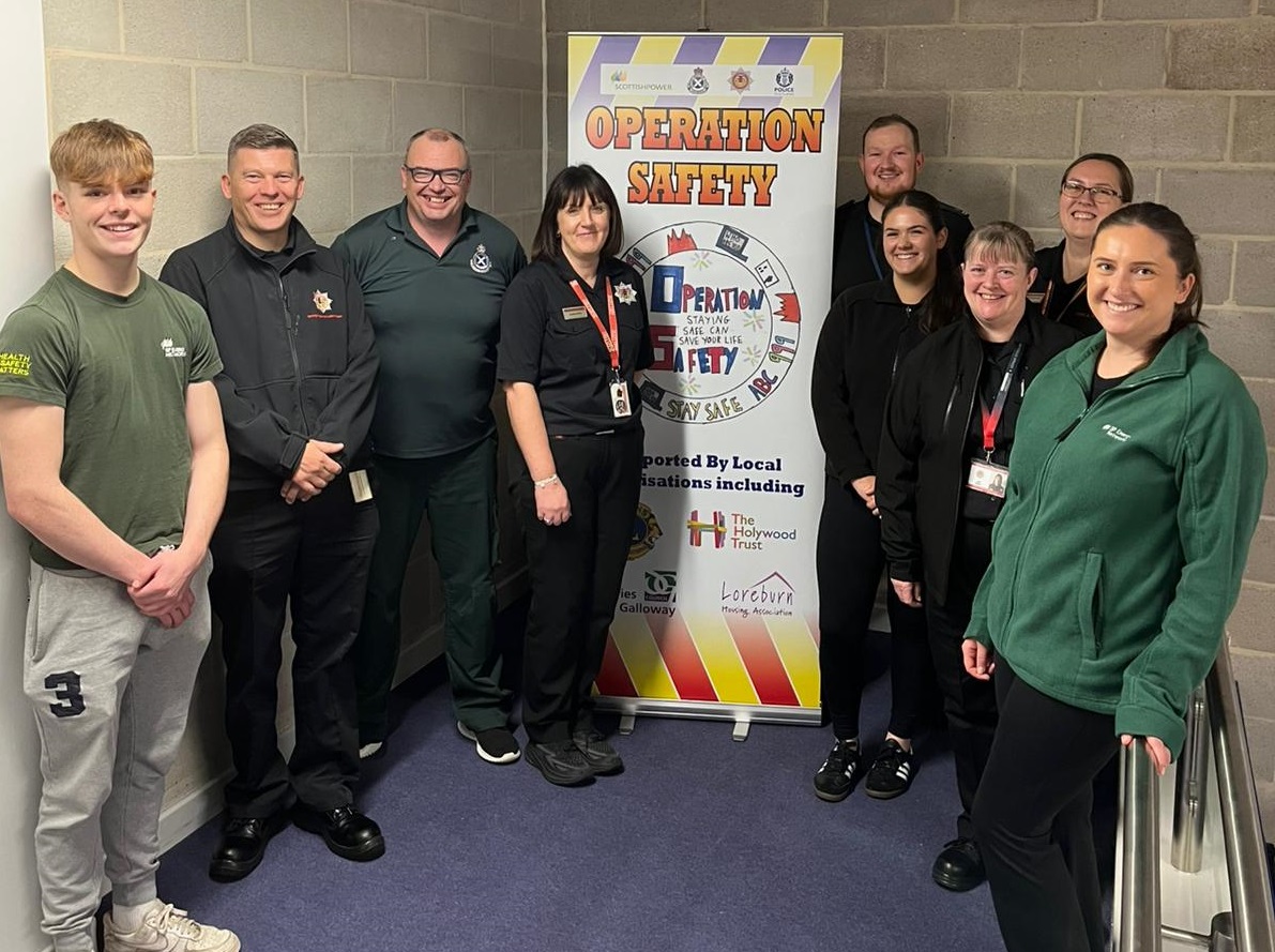 Group of 9 people stood around an Operation Safety pull up banner.