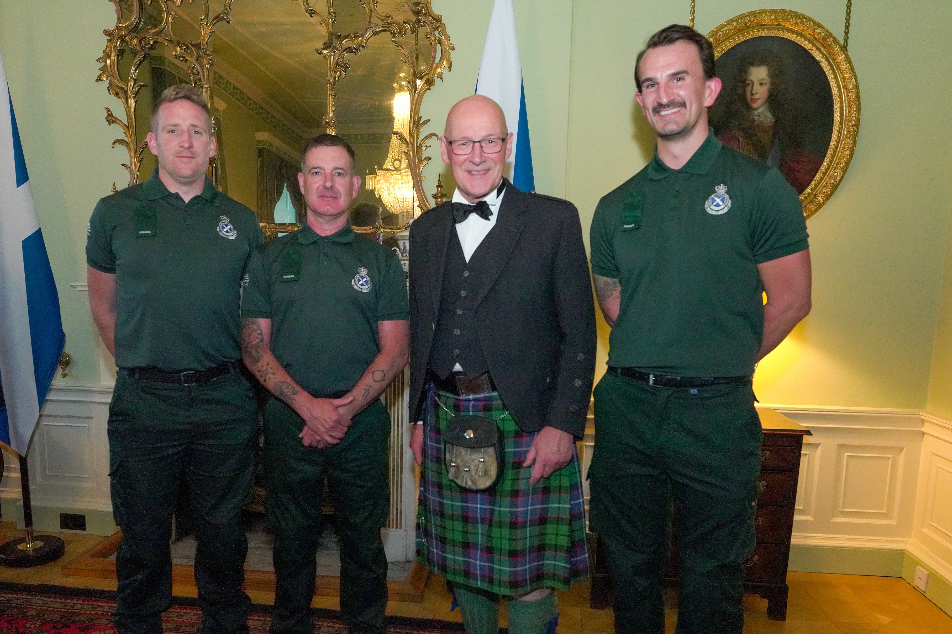Three SAS emergency response staff stand with First Minister John Swinney