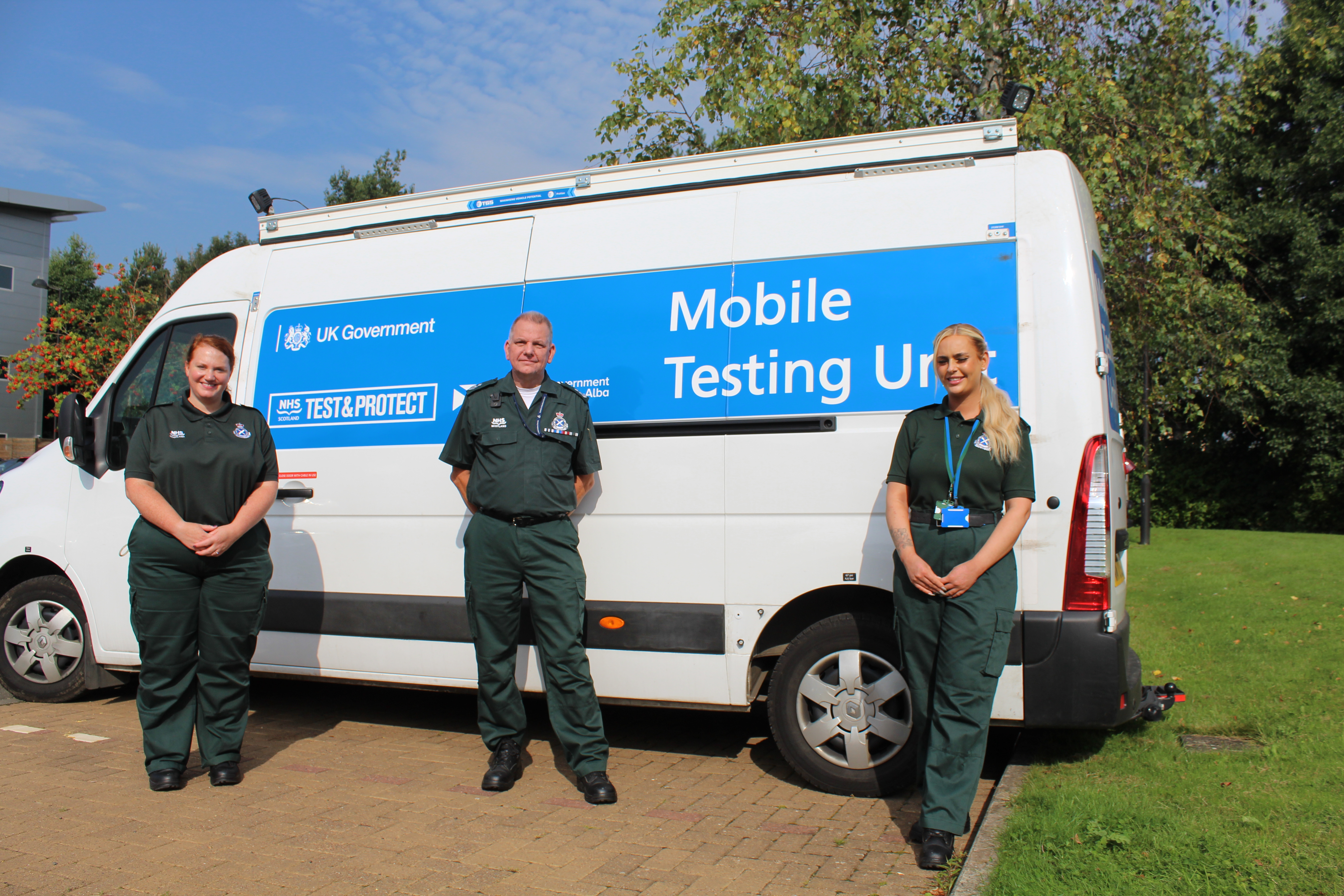 Three members of staff in front of a mobile testing unit
