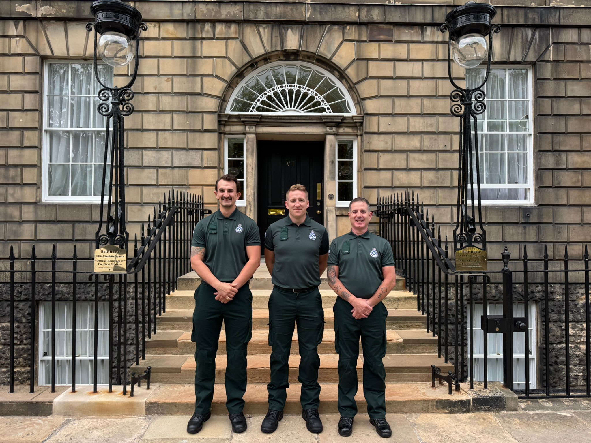 Three SAS staff members stand proudly out of the front of Bute House before the reception