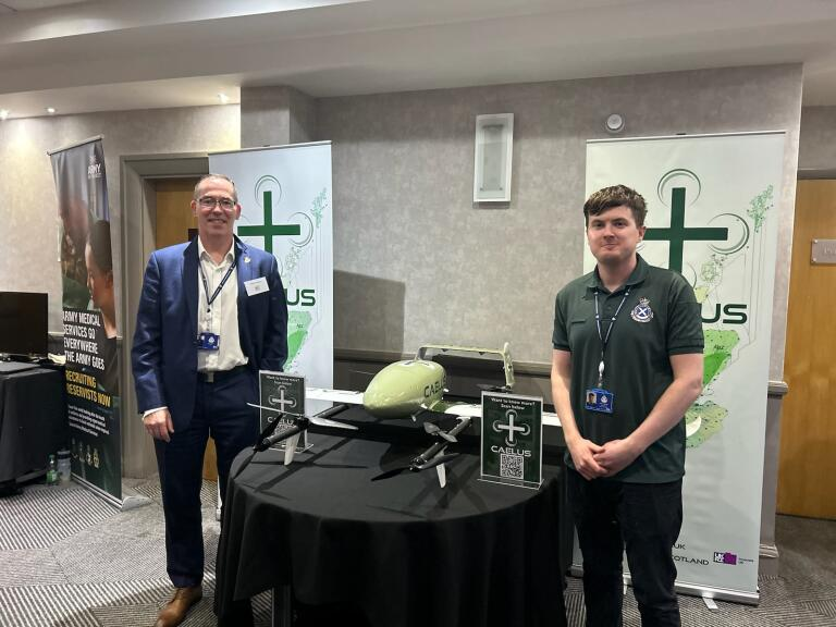 Scottish Ambulance Service Chief Executive Michael Dickson and CAELUS project manager Shaun Marshall stand next to a table with a drone on it 