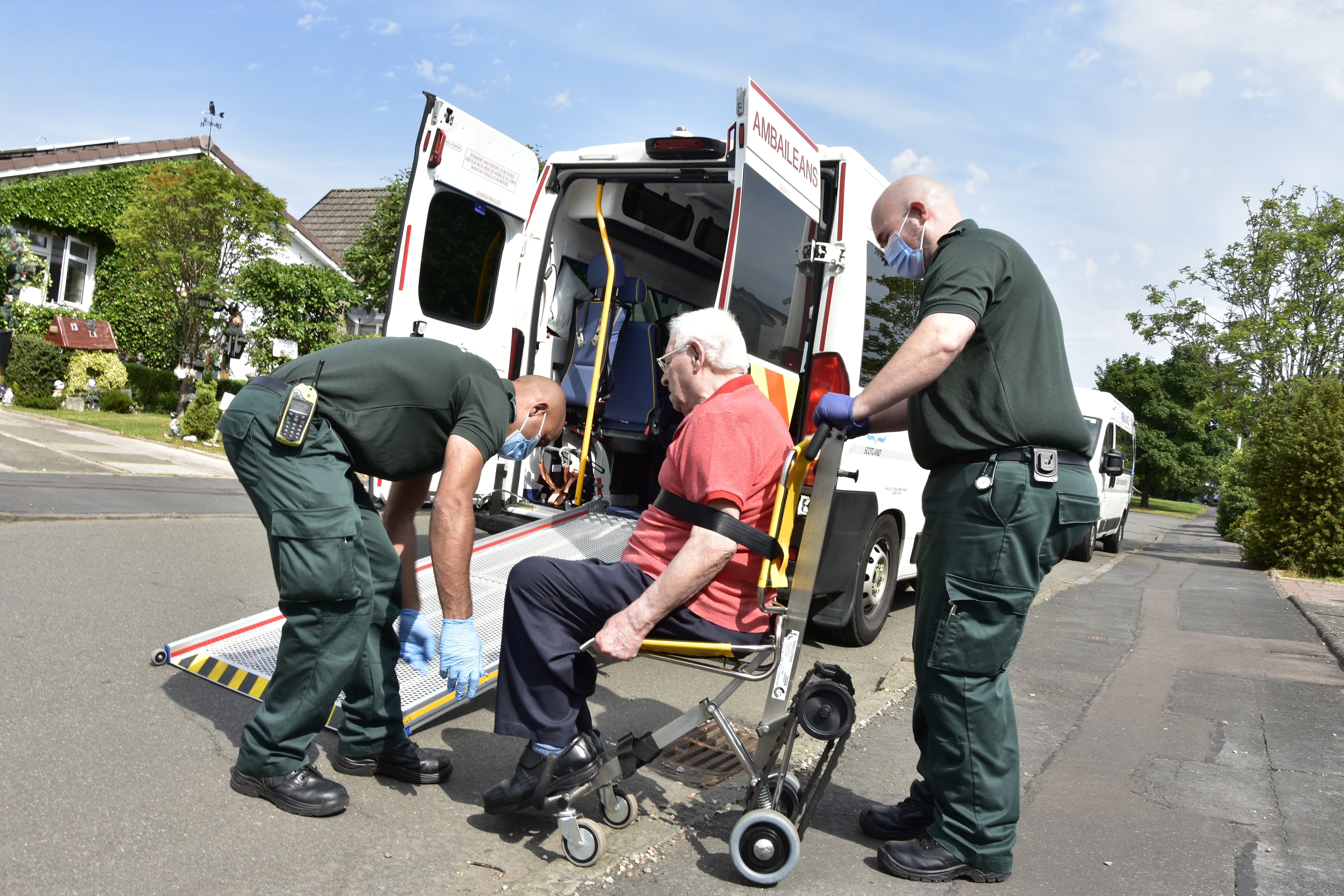 Two Ambulance Care Assistants help a patient onto an ambulance