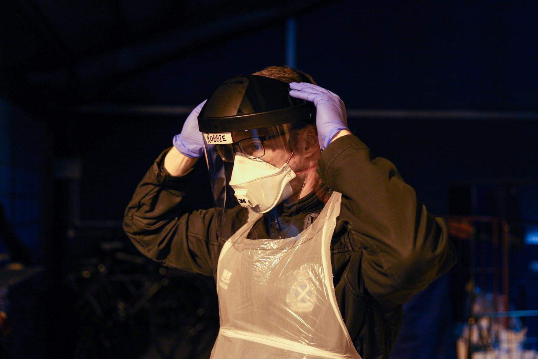 A Scottish Ambulance Service staff member stands ready to attend a job in mask and gloves during Covid