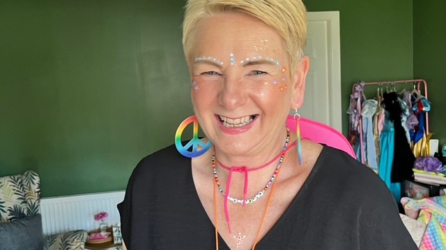 Eileen with a big smile on her face dressed in rainbow apparel 