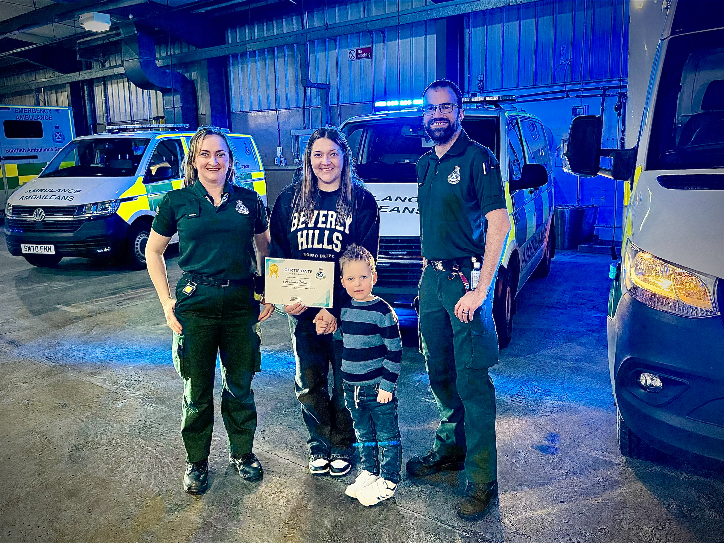 Brave Joshua stands proud with his certificate with his mum and the crew watching on