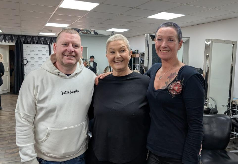 The 3 Scottish Ambulance Service staff members with their hair saved off stand proudly at the hair salon