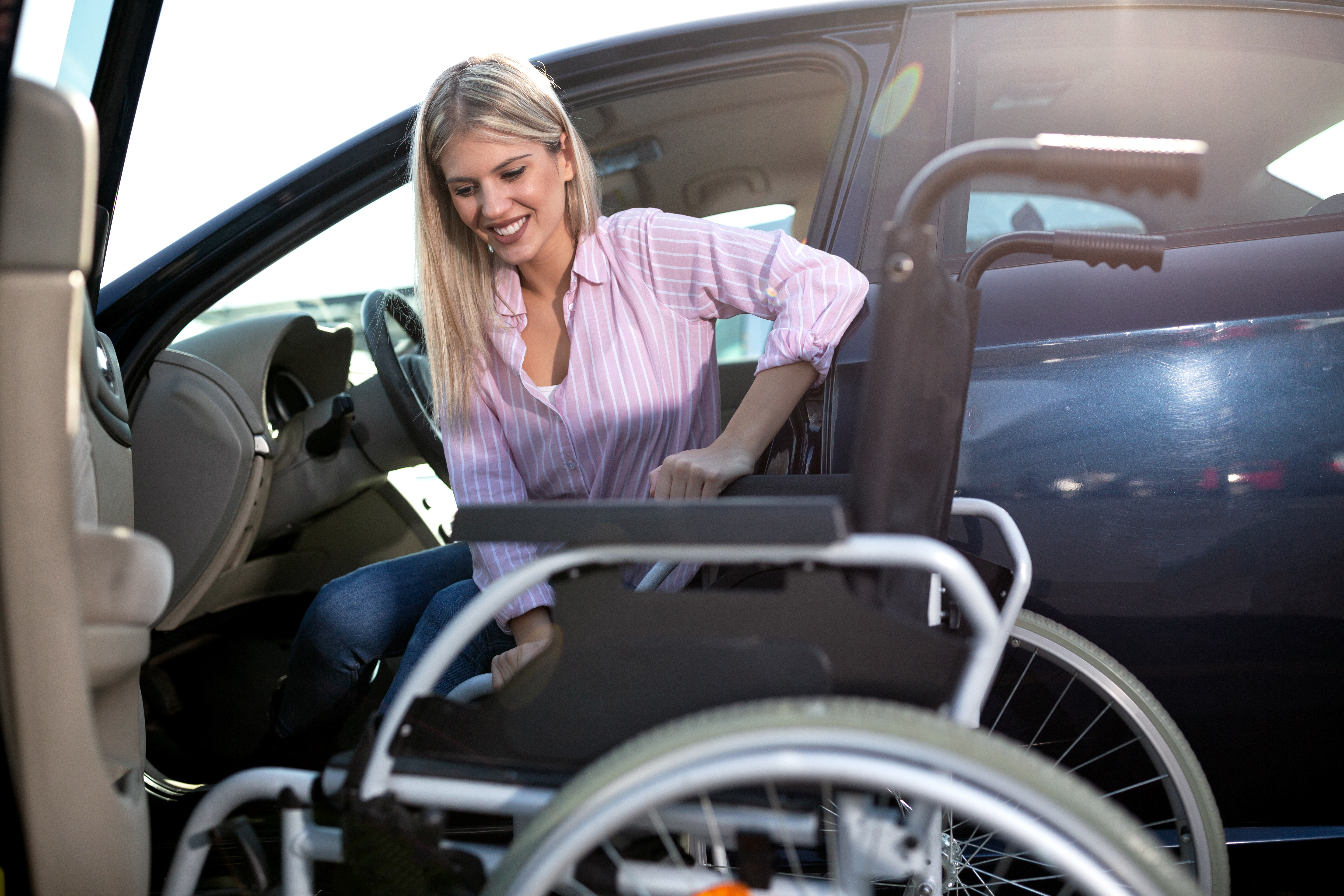 A woman getting out of car into a wheelchair