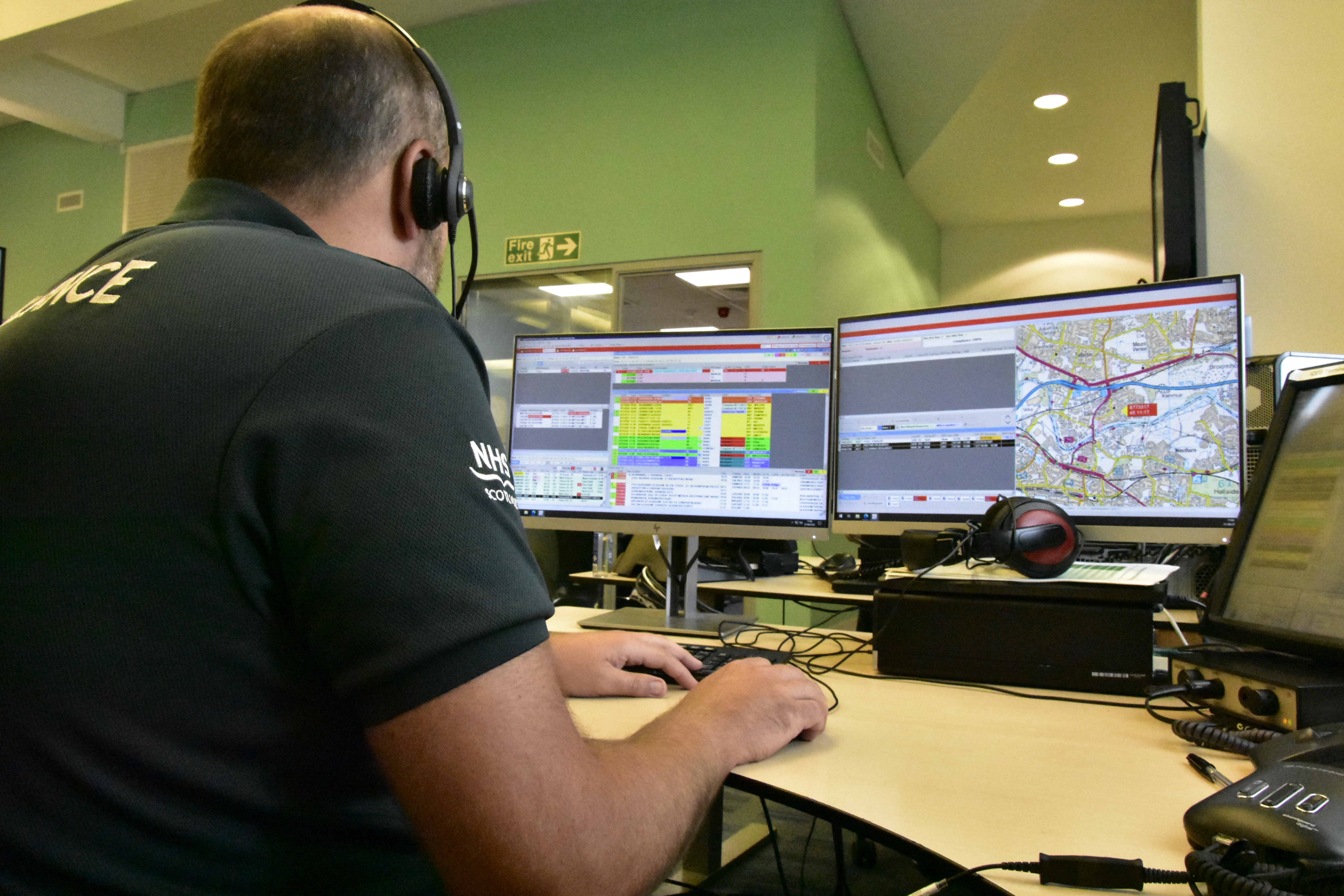 ACC call handler taking a call in front of two screens