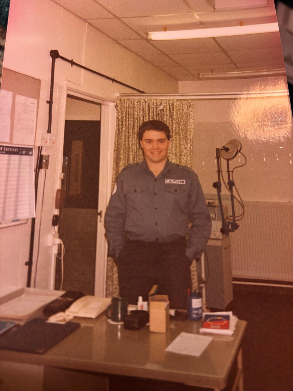 Calum stands smiling in his old navy uniform