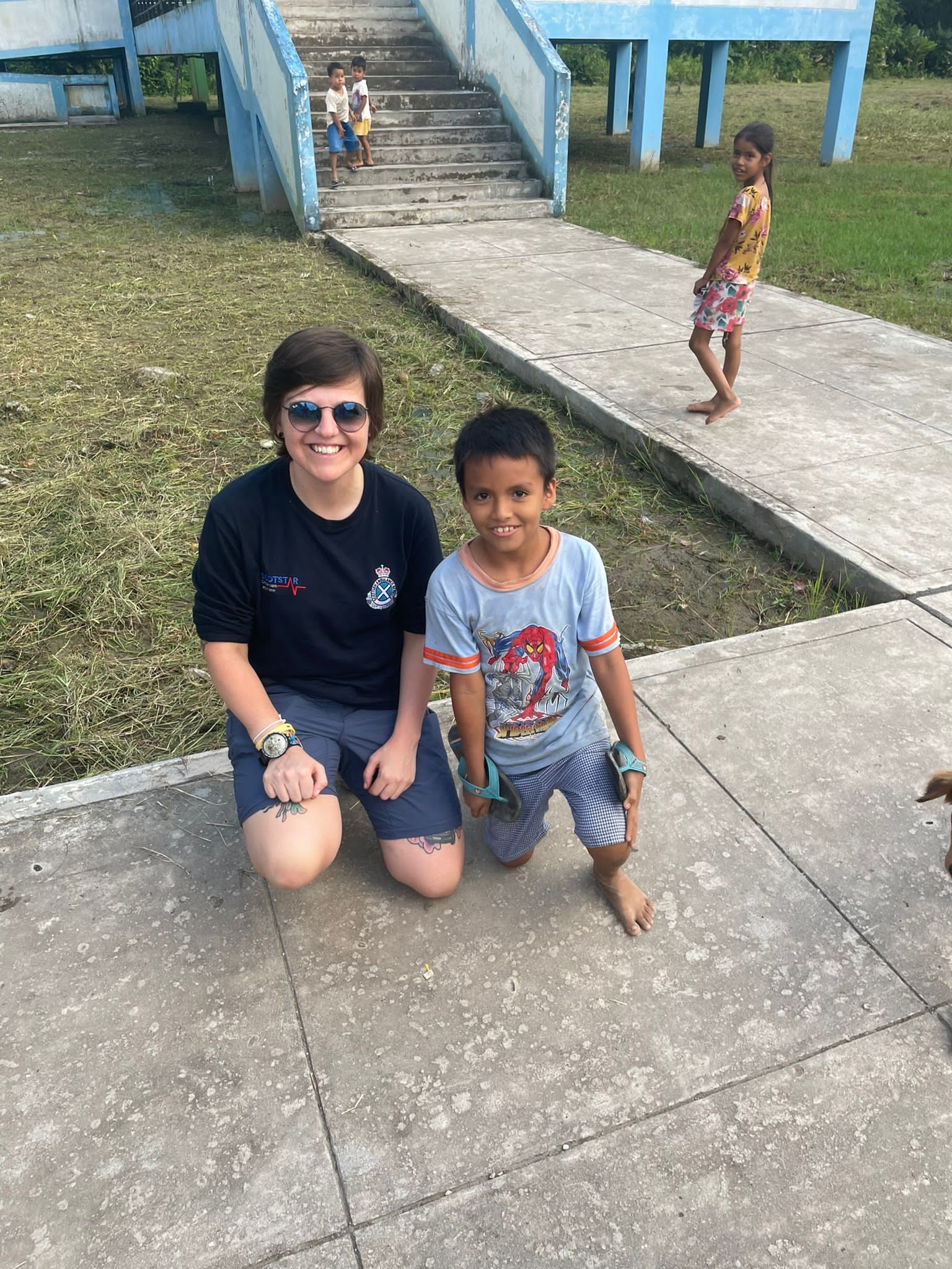 Kelly Irvine kneeling next to a young boy, both are smiling at the camera.