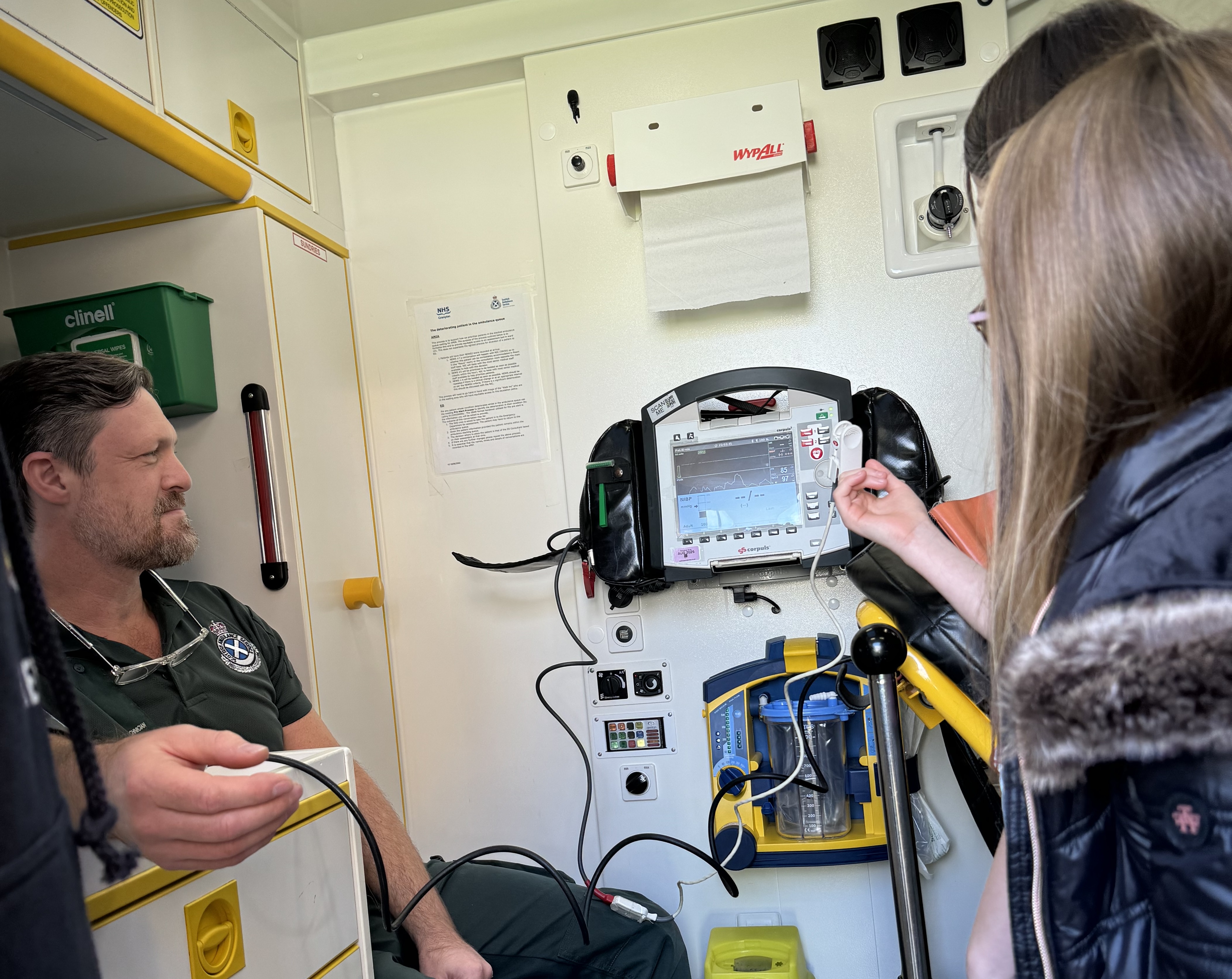 A SAS staff member shows young Hayley how to use a defib in the back of an ambulance