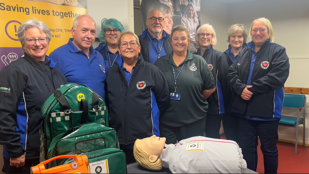 A group of 8 community first responders and one paramedic standing and smiling at the camera.